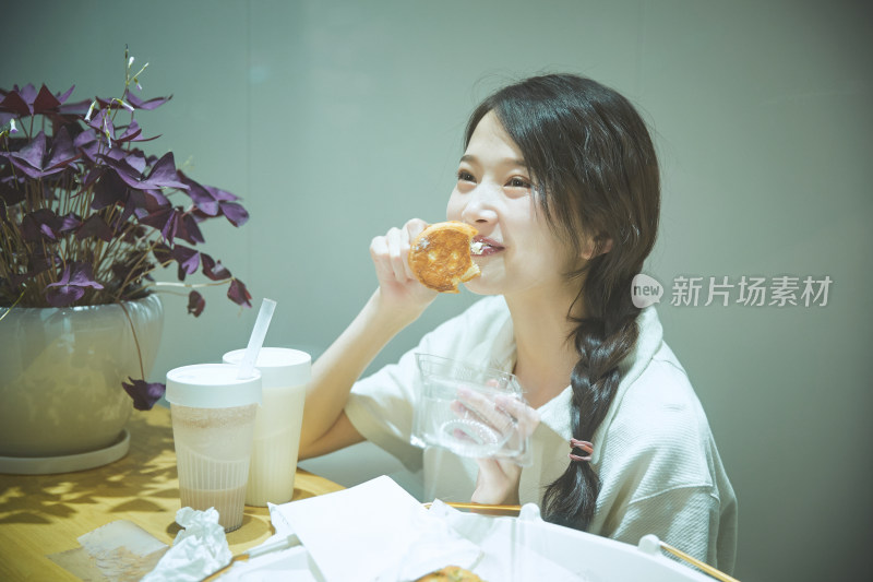 在烘焙店吃面包喝牛奶的可爱亚洲少女