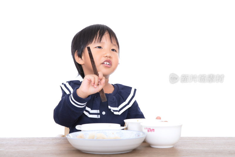 白背景前餐桌旁的小女孩在吃饭