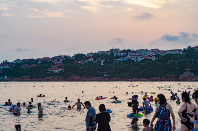 青岛海水浴场，许多人在游泳玩耍