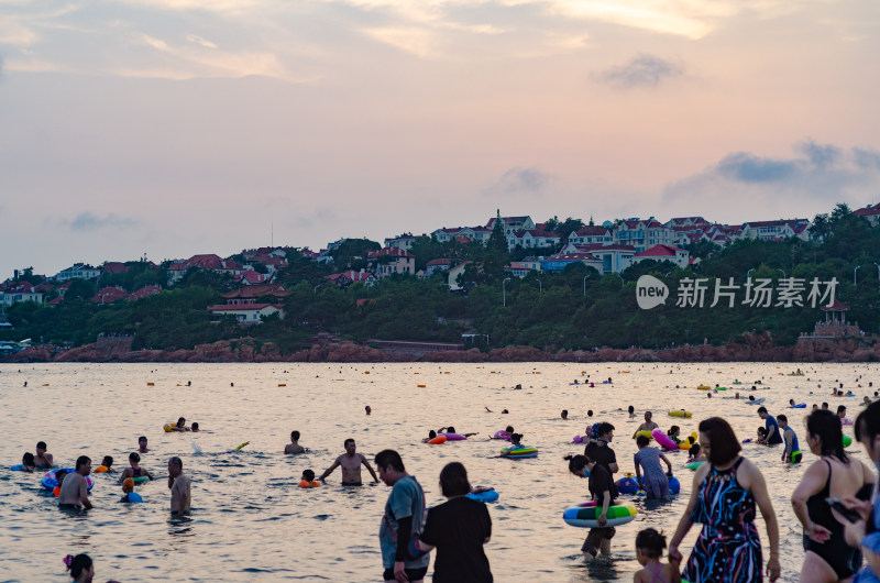 青岛海水浴场，许多人在游泳玩耍