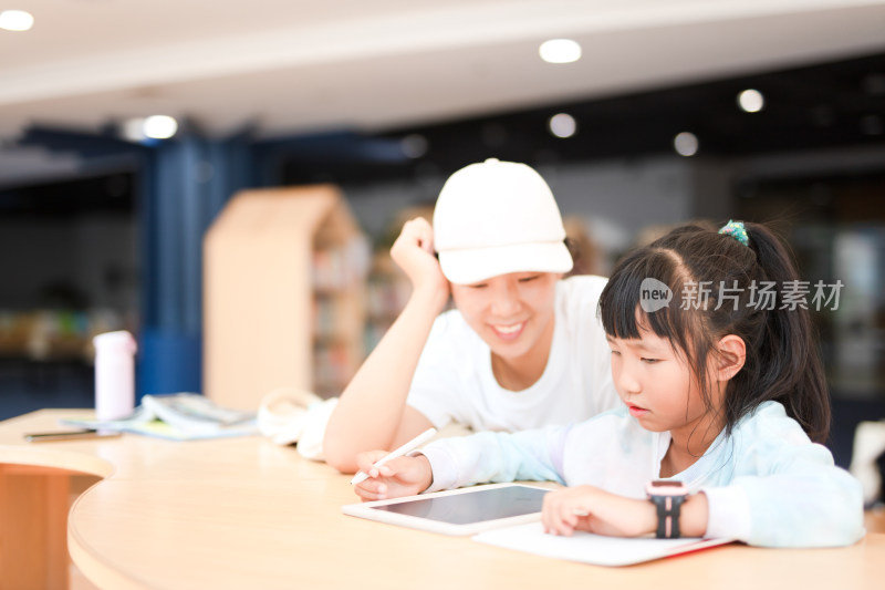 妈妈认真辅导女儿学习在图书馆