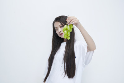 吃葡萄的穿白色长T血衫的长发可爱少女人像