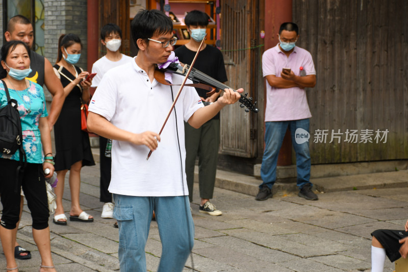 街头男子拉小提琴吸引路人