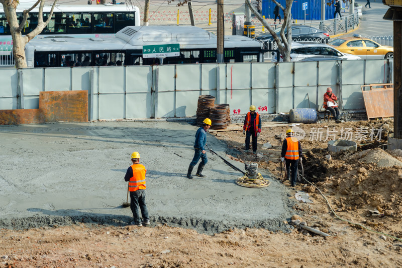 建筑工地，工人正在使用路面抹平机平整路面