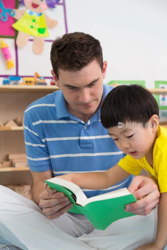幼儿园外教男老师和儿童一起看书