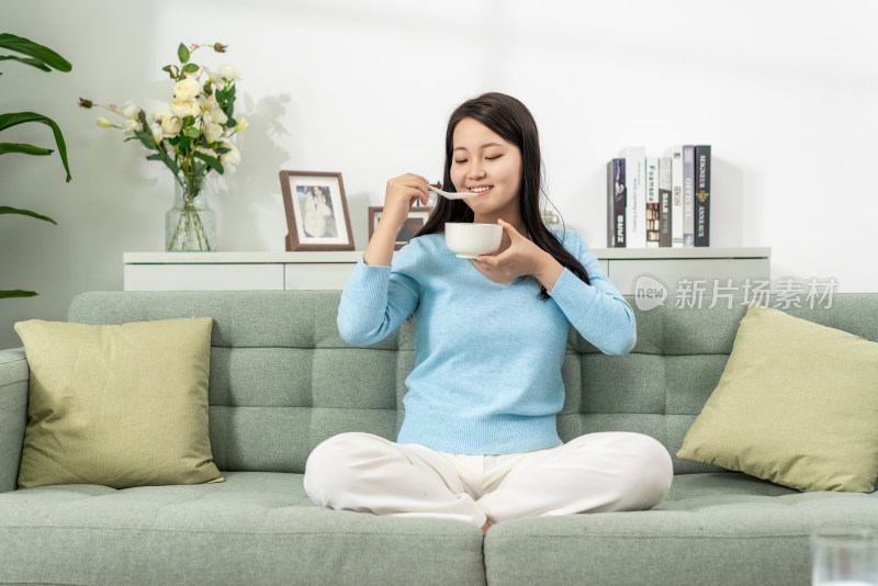 一位年轻女士在家吃早餐喝粥