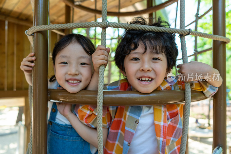 两个小孩子开心爬绳网攀爬架