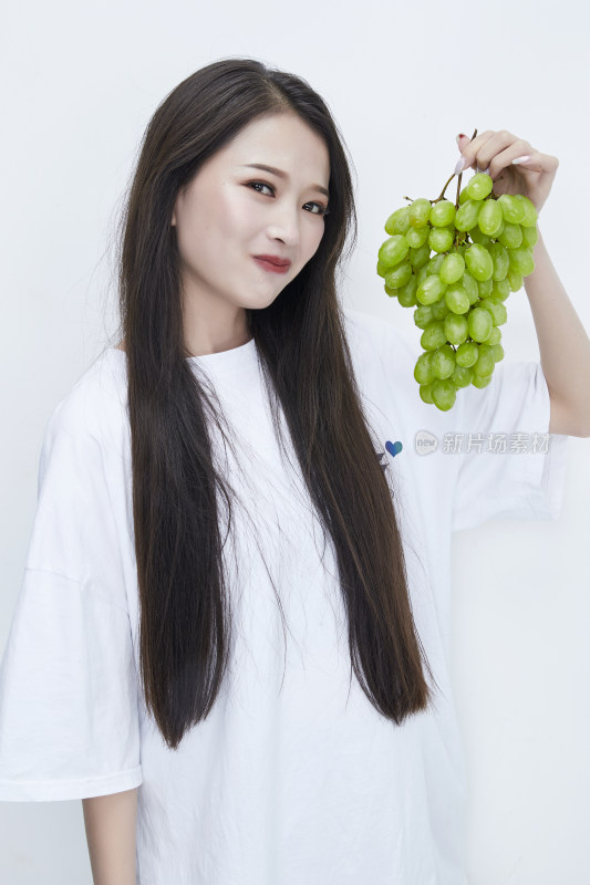 吃葡萄的穿白色长T血衫的长发可爱少女人像