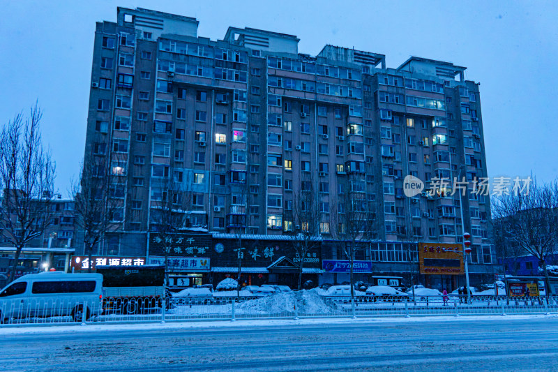 雪天夜晚亮灯的居民楼外景马路街道