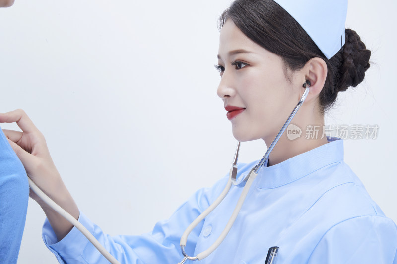 佩戴听诊器的女性医护人员为患者听诊检查