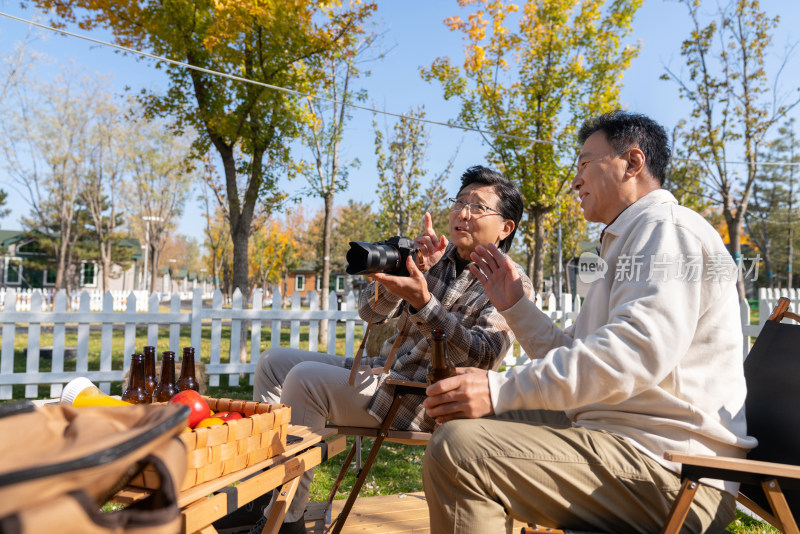 两个老年男人坐在露营地看数码相机