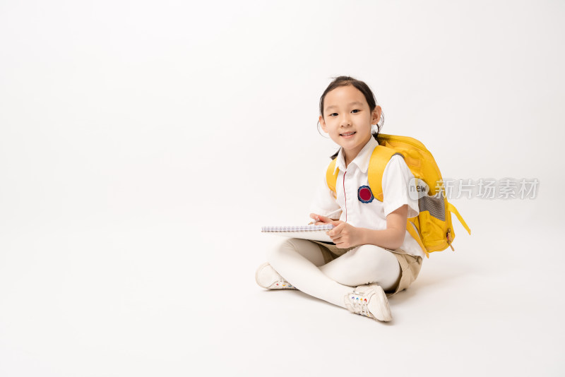 坐在白色背景前在作业本书上写的中国女孩