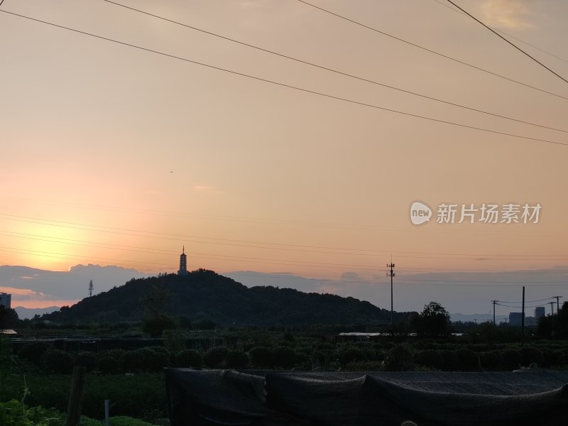 夕阳下的山丘及山上的古塔