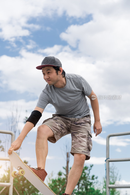 夏天在公园玩滑板的亚洲男性
