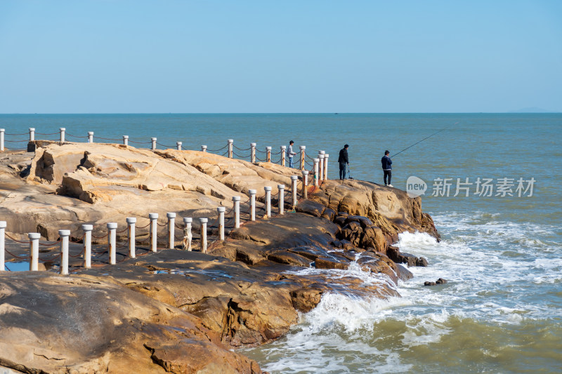 海边岩石上的人垂钓