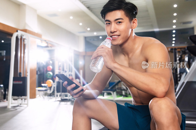 青年男人在健身房里喝水