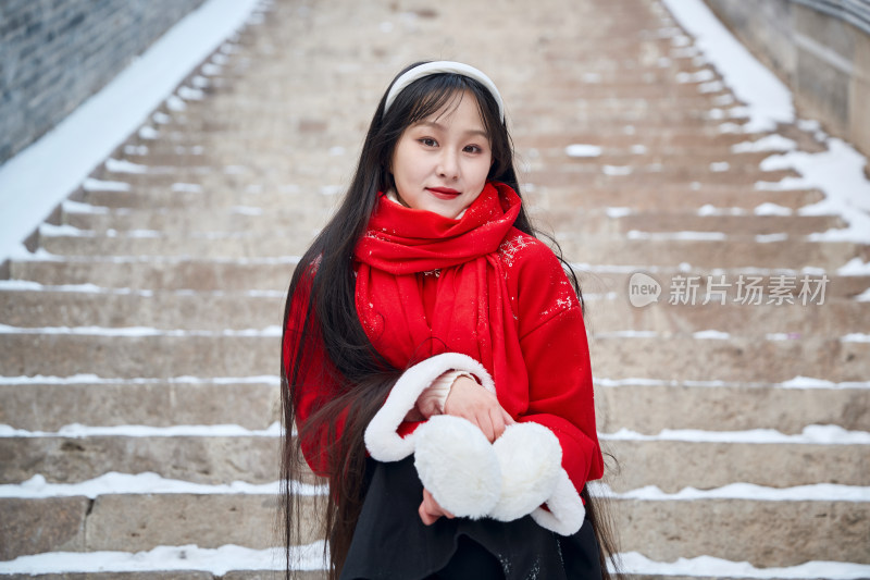 雪后在老城古巷穿着喜庆服饰的亚洲少女