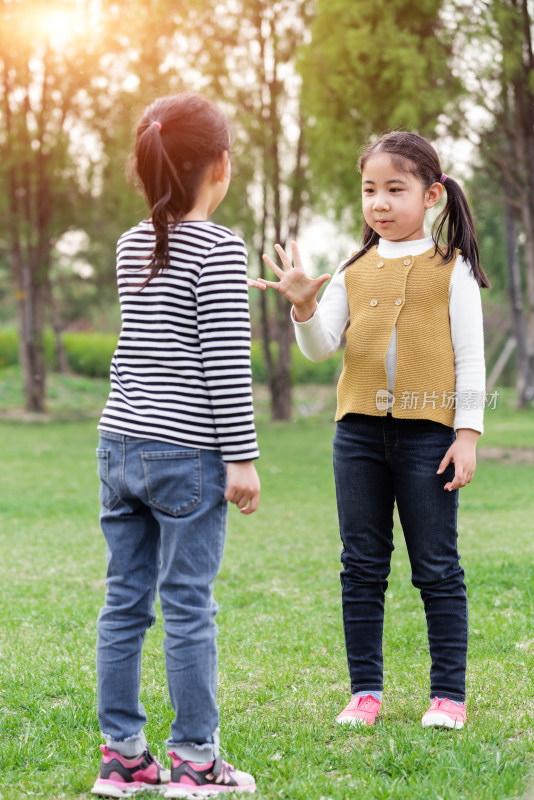 两个在草坪上玩吹泡泡游戏的女孩