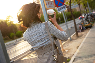 青年女人拿着饮料走在马路上