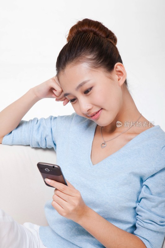 年轻女人坐在沙发上打手机