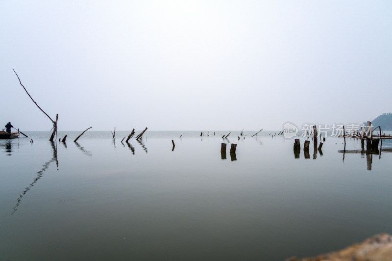 秋季水库早晨湖边钓鱼人与木桩