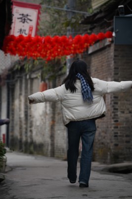 穿冬装女子在挂有红灯笼的古镇小巷行走