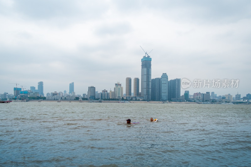 城市水域中游泳的人背后是高楼大厦