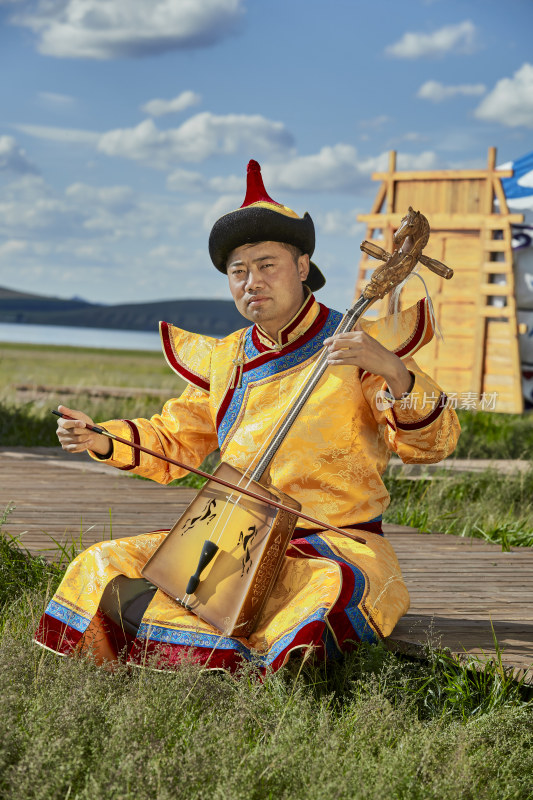 蒙古包前身穿蒙古族服饰拉马头琴的男子