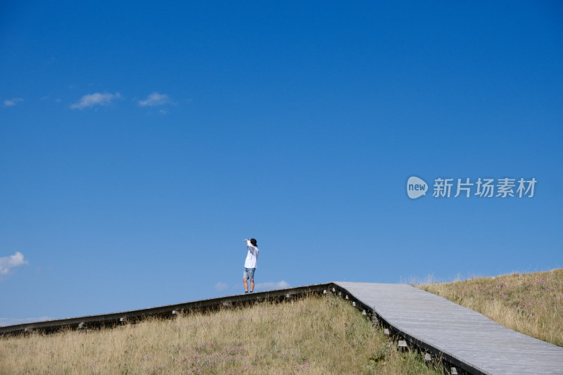 户外草原栈道上的单人观景场景