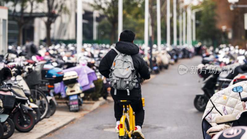 男子骑行于停放众多电动车的街道