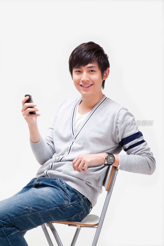 年轻男人做在椅子上使用手机