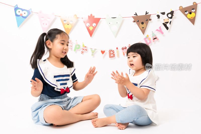 两名坐在白色背景前游戏的中国女孩