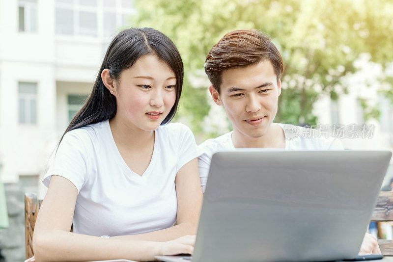 两位年轻人一起使用笔记本电脑
