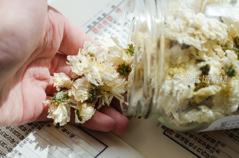 手从罐中取干菊花