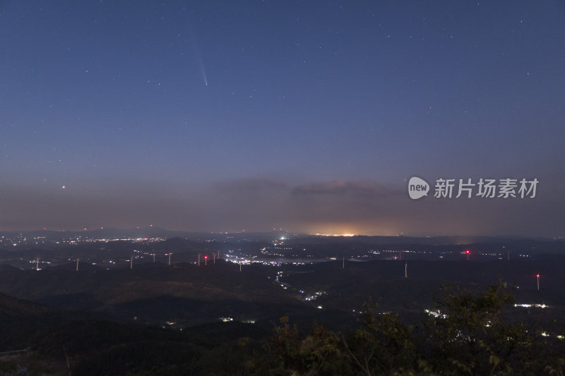 城市上空夜晚彗星落下山间风车群的壮观景象