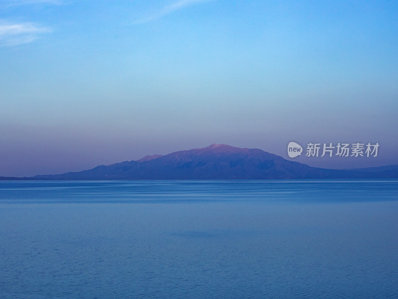 安静的蓝色海平面和远处山上的日落