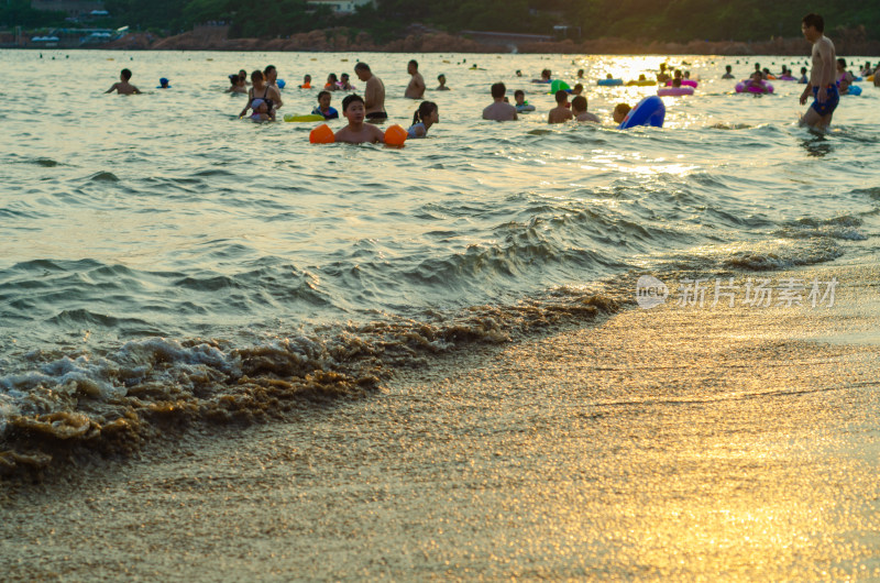 青岛汇泉湾夕阳下，海水浴场中的人们