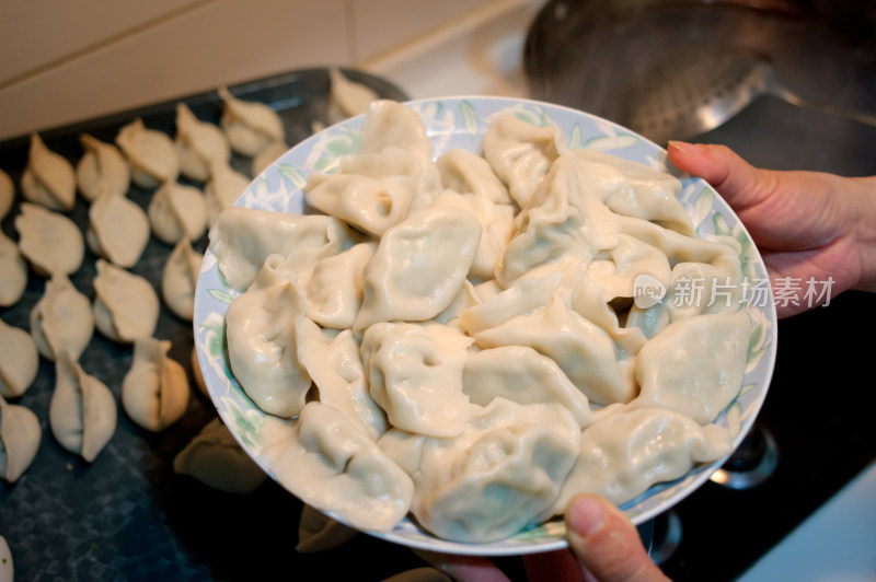 厨房灶台上煮水饺和待下锅的饺子