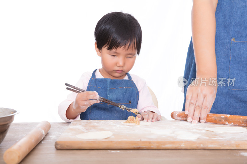 中国小姑娘在妈妈身旁认真的学习包饺子