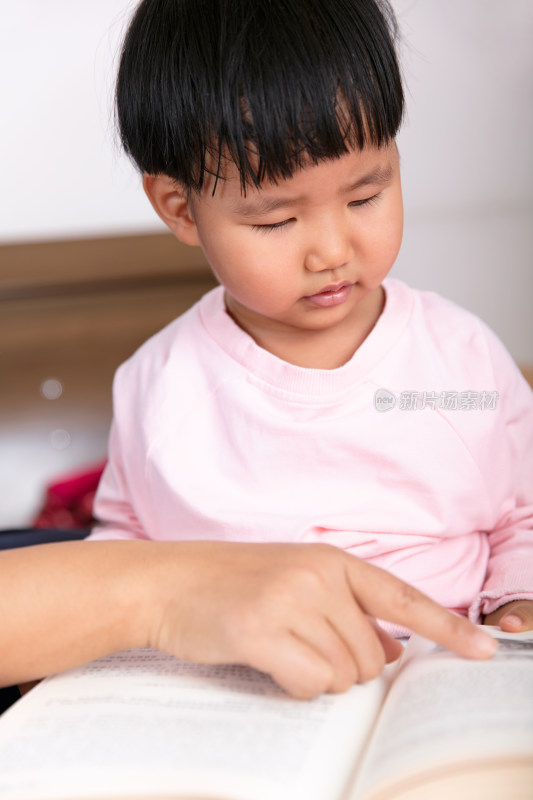 特写把书本摊在腿上看书的小孩子