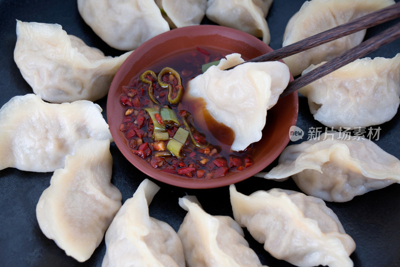 盘子里的饺子蘸进醋和辣椒调制的蘸料中