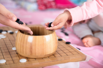 一只小手正把棋子放入棋盒中