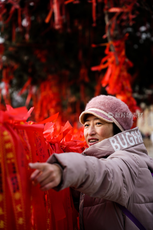 身穿厚外套的女士指着红色祈福带