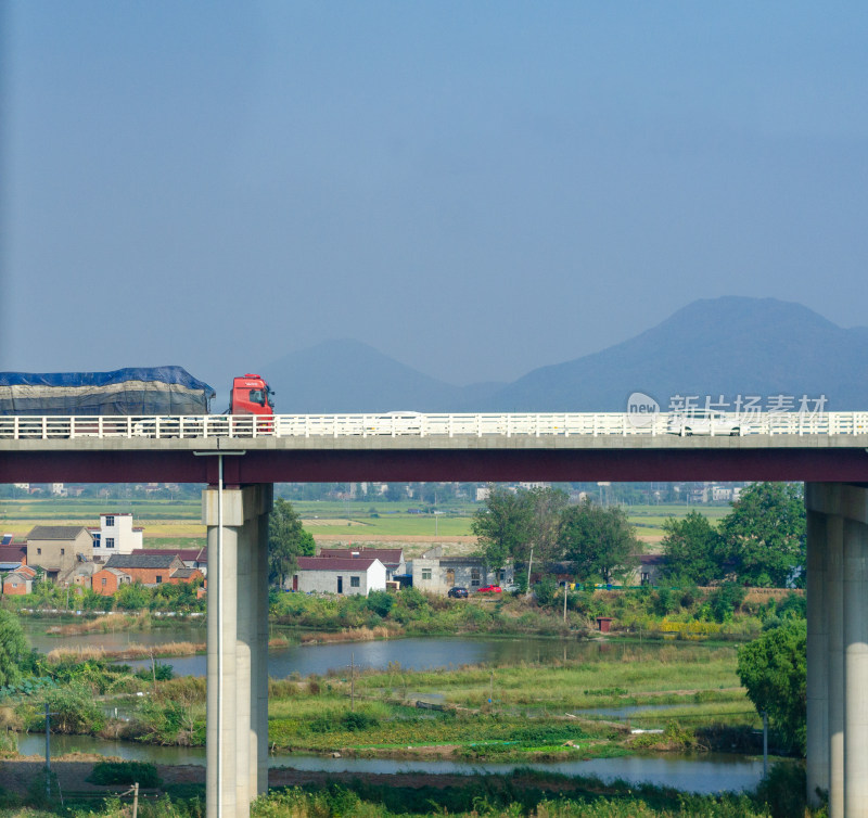 村庄旁大桥上驶过卡车