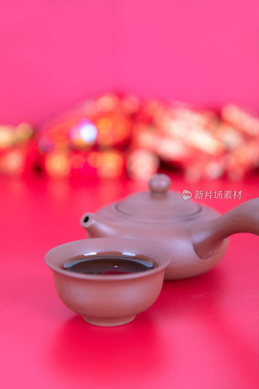 红背景上的紫砂把壶和茶碗