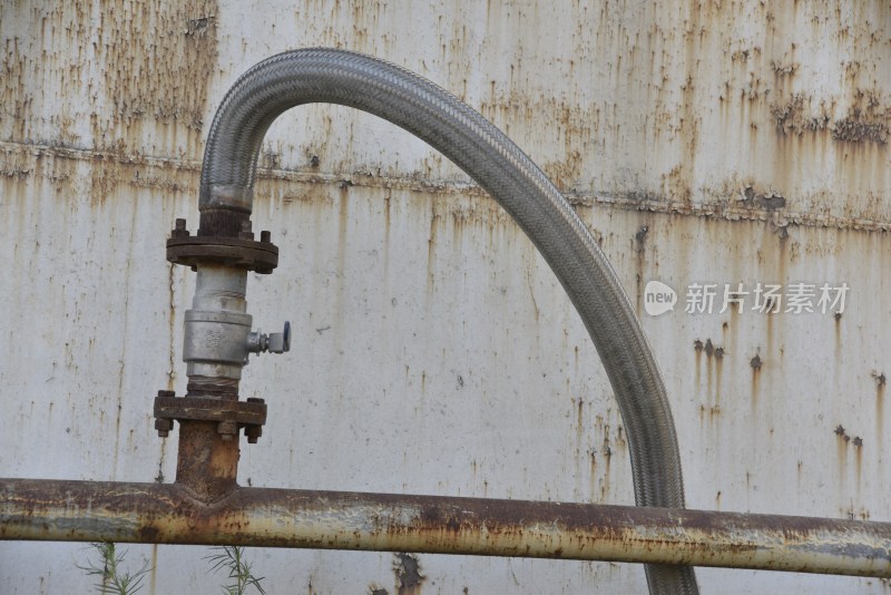 生锈金属墙前的工业软管阀门