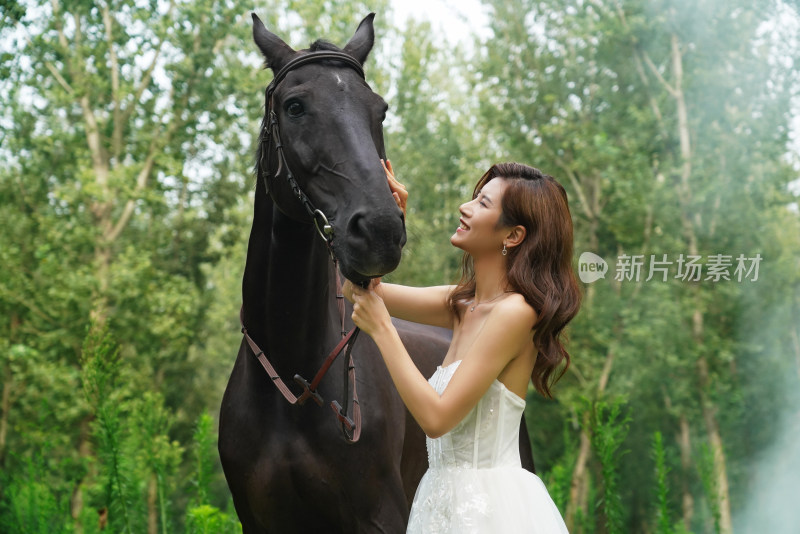 漂亮的年轻女人亲昵的抚摸着马