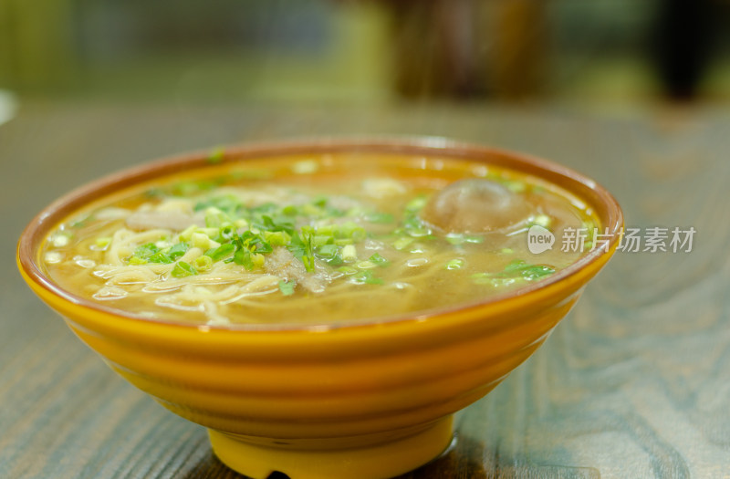 木桌一大碗加了卤蛋和葱花的牛肉拉面