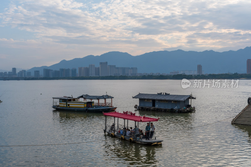 江上小船游弋，远山城市背景相衬