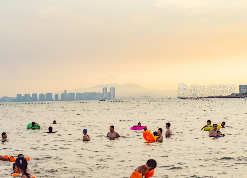 青岛汇泉湾夕阳下，海水浴场中的人们